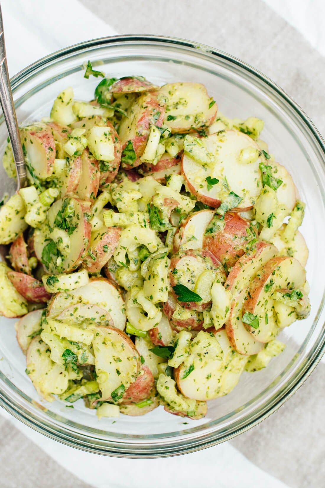 This simple, herbed red potato salad recipe will be a hit at your next potluck! The light, creamy sauce is mayo-free, and this recipe is vegan! cookieandkate.com